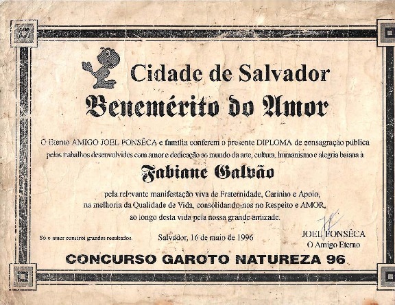 Documento digitalizado. A página foi restaurada e encontra-se habilitada para leitura OCR. Trata-se basicamente de um documento digitalizado, com diversas marcas de dobradura e desgaste. Na imagem, há um louro pequeno em desenho no canto esquerdo ao lado da frase “CIDADE DE SALVADOR” acima da frase “BENEMÉRITO DO AMOR”, com o nome Fabiane Galvão centralizado, a assinatura de Joel Fonsêca (O amigo eterno) e os seguintes dizeres “O eterno AMIGO JOEL FONSÊCA e família conferem o presente DIPLOMA de consagração pública pelos trabalhos desenvolvidos com amor e dedicação no mundo da arte, cultura, humanismo e alegria baiana e Fabiane Galvão pela relevante manifestação viva de Fraternidade, Carinho e Apoio na melhoria da Qualidade de Vida, consolidando-nos no Respeito e AMOR, ao longo desta vida pela nossa grande amizade.” Abaixo a frase “Só o amor constrói grandes resultados” em tamanho pequeno. E em caixa alta e negrito a frase “Concurso Garoto Natureza 96”.