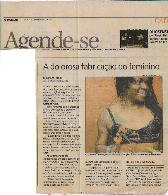 Recorte de jornal impresso digitalizado, restaurado e habilitada para leitura OCR. A página está cortada no canto esquerdo, mas não prejudica a leitura da reportagem. Há, no centro da reportagem, uma marca de dobra de página de jornal. A matéria, “A dolorosa fabricação do feminino”, está disponível na íntegra. Na direita, uma foto do busto para cima de Tâmara Taxman (em memória) sorrindo em top preto com brilhantes prateados, cabelos pretos ondulados abaixo do ombro e tatuagens no ombro direito. Em sua frente flores alaranjadas/avermelhadas.